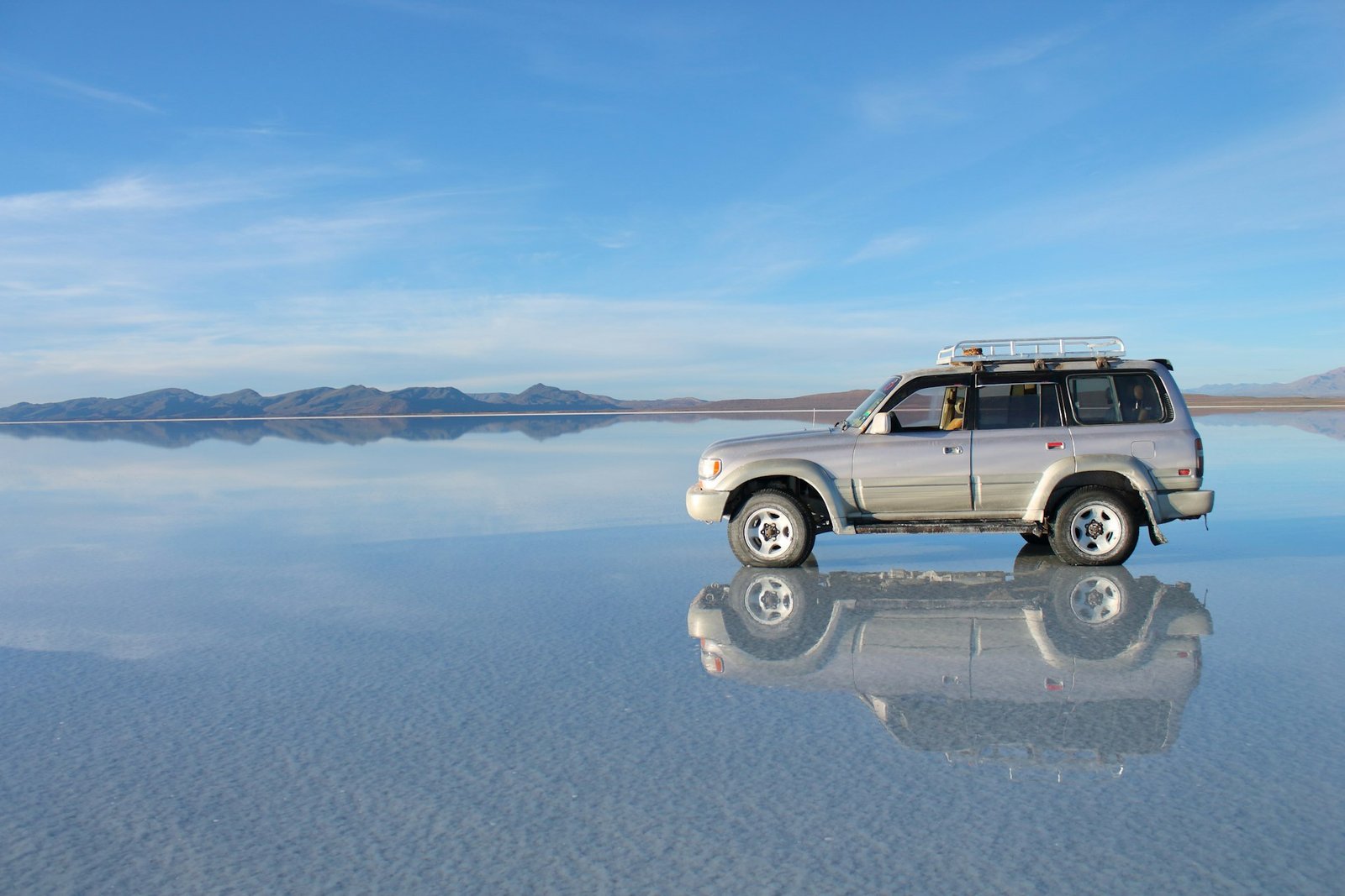 Vehículo sobre el espejo de agua del Salar de Uyuni durante una luna de miel en Bolivia