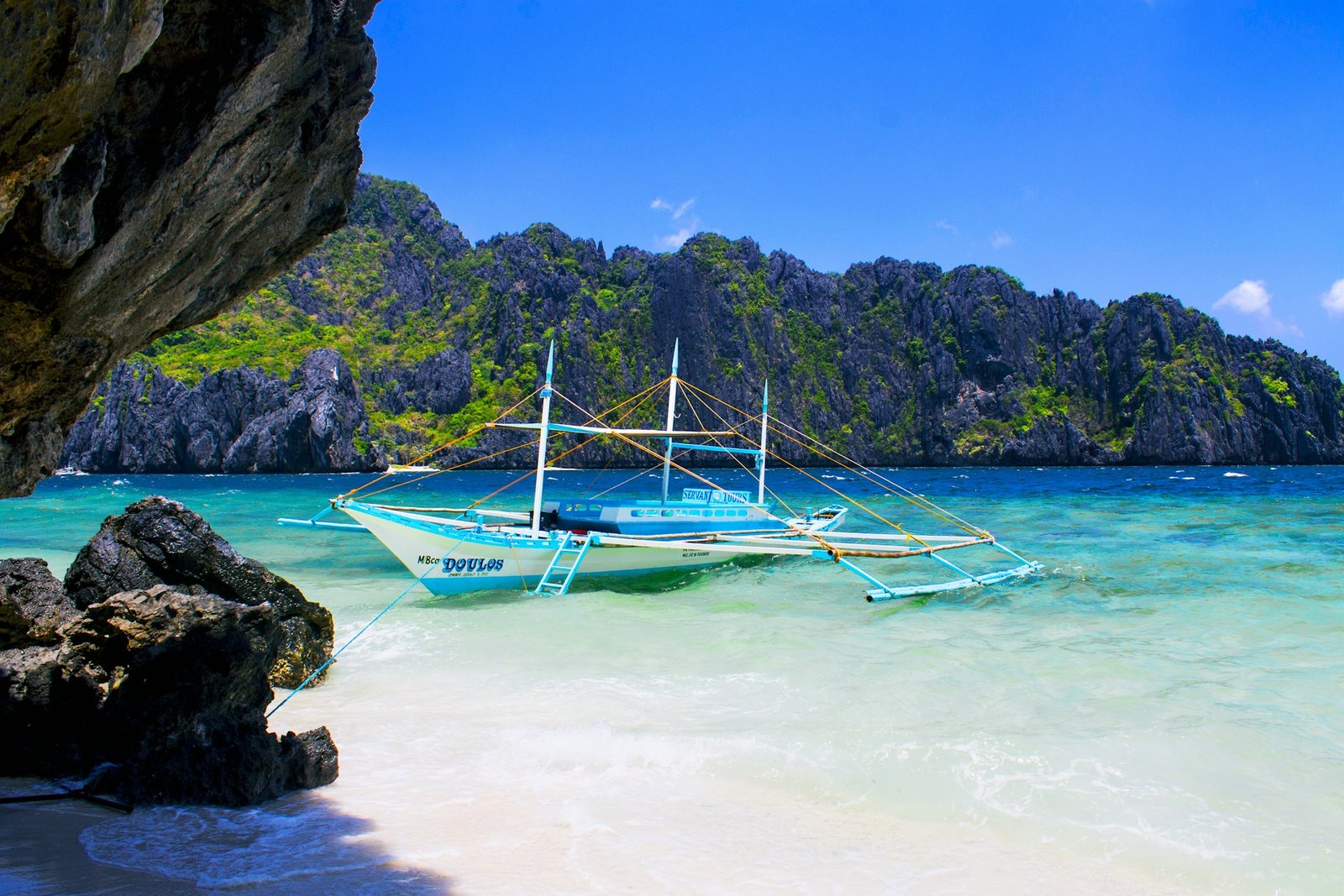 Barco tradicional filipino en una playa de arena blanca de Palawan, en una luna de miel en Filipinas