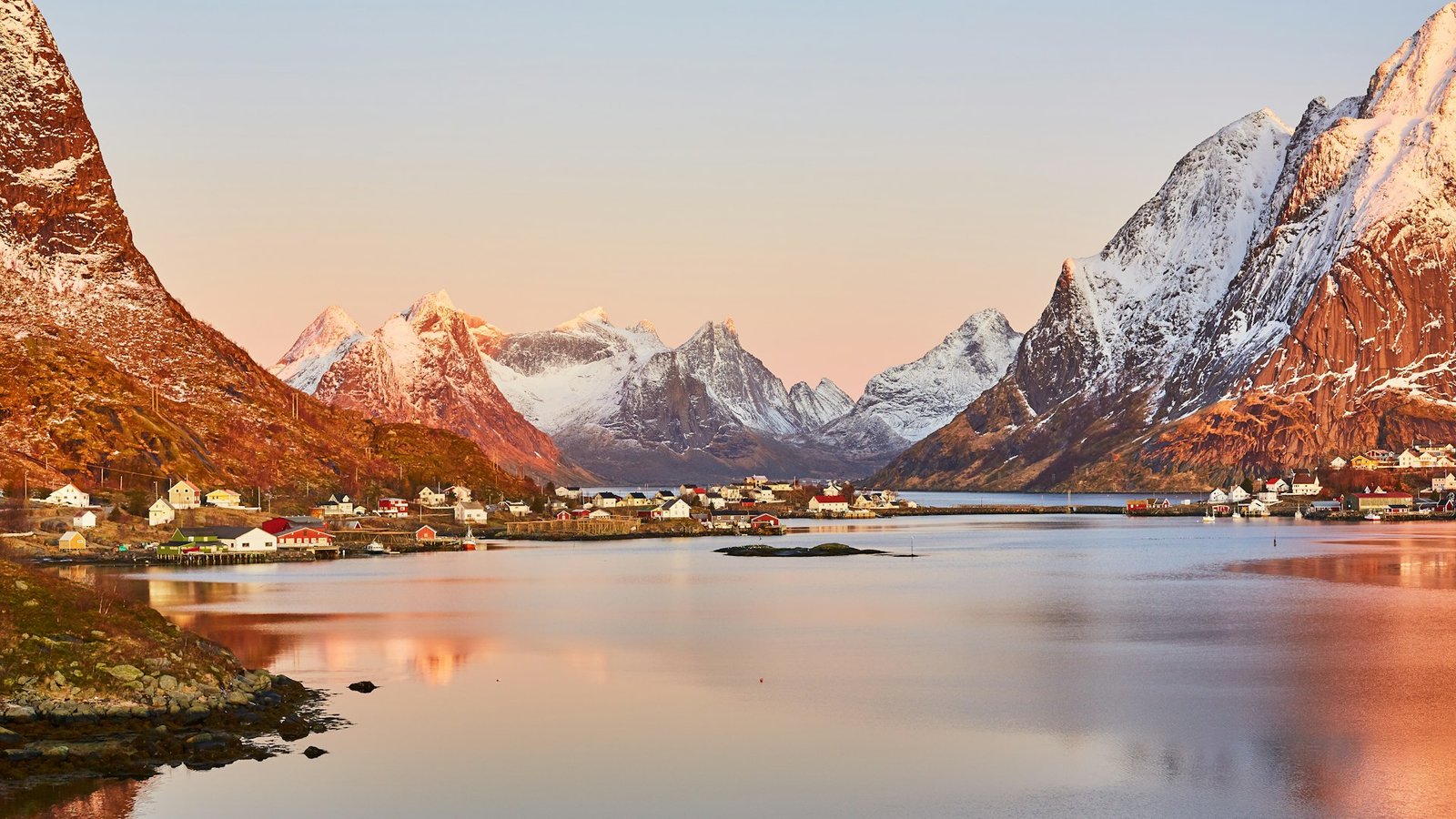 Atardecer sobre montañas nevadas reflejadas en el mar en el norte de Noruega