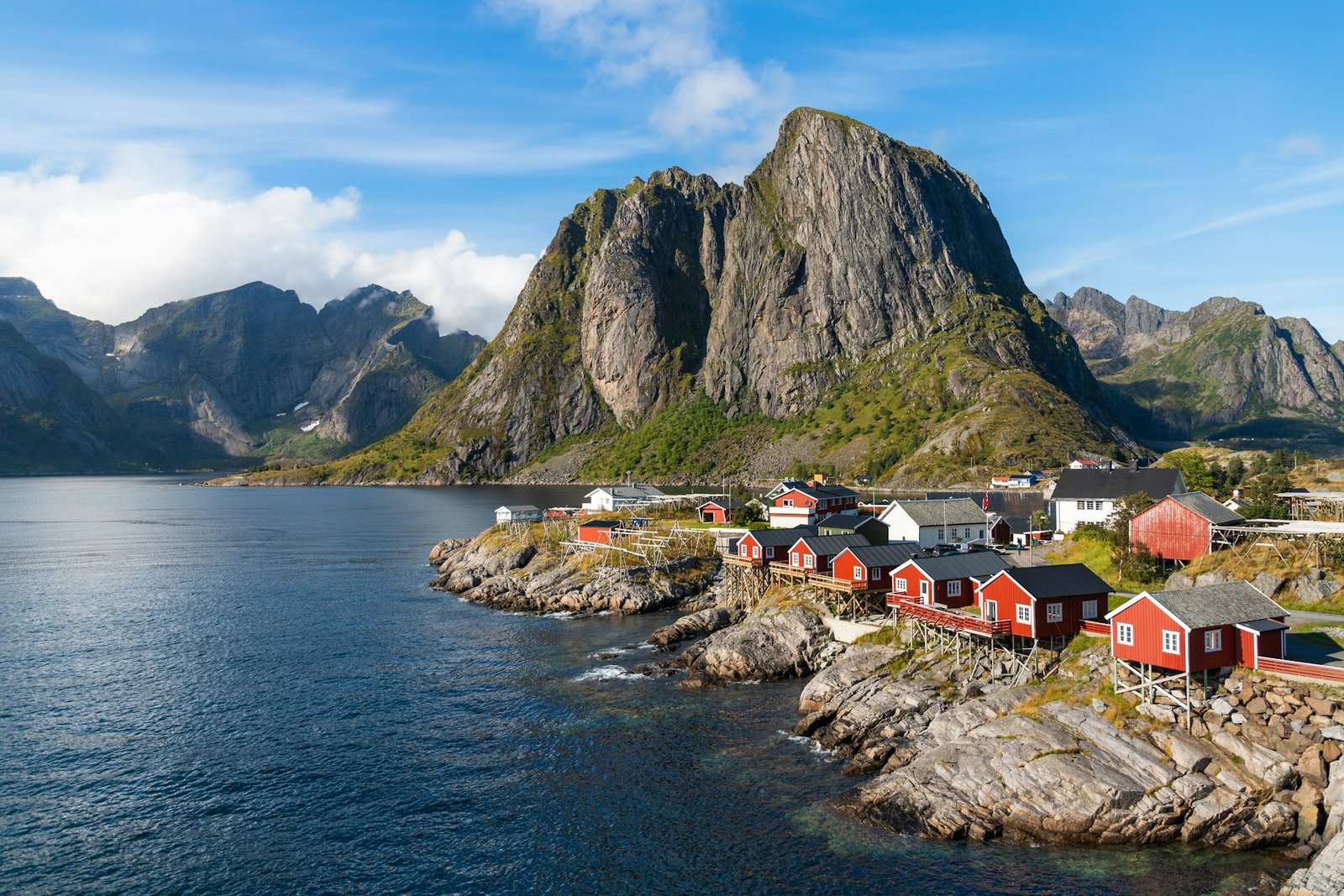 Pueblo de pescadores con cabañas rojas bajo una montaña en las Lofoten, luna de miel en Noruega