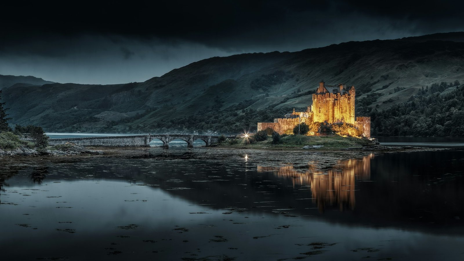 Castillo de Eilean Donan iluminado al anochecer junto al lago, mejor época para viajar a Escocia